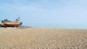 A pebbled beach with a wooden boat and a small boat docked on the shore. - A great base for seaside enthusiasts. (Deal)