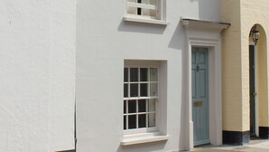 A building with white walls, a blue door, and a window with white frames. - A great base for seaside enthusiasts. (Deal)