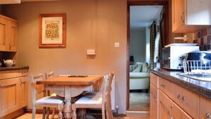 A kitchen with wooden cabinets, a dining table with chairs, and a framed picture on the wall. - 2 bedroom accommodation in Bussage, near Cirencester (Bussage, near Cirencester)