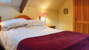 A bedroom with a bed, a wooden headboard, a red blanket, a bedside lamp, and a wooden wardrobe. - 2 bedroom accommodation in Bussage, near Cirencester (Bussage, near Cirencester)