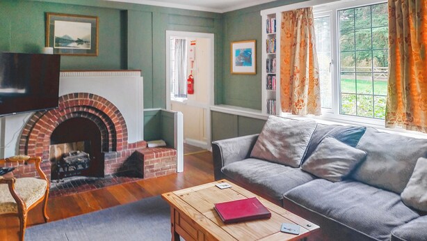 A cozy living room with a fireplace, a sofa, a wooden coffee table, and a bookshelf. - 3 bedroom accommodation in Llanddona, near Beaumaris (Llanddona, near Beaumaris)