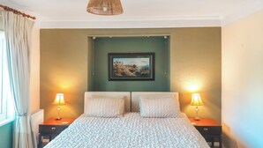 A bedroom with a large bed, two bedside tables, a hanging light fixture, and a framed picture on the wall. - 3 bedroom accommodation in Llanddona, near Beaumaris (Llanddona, near Beaumaris)