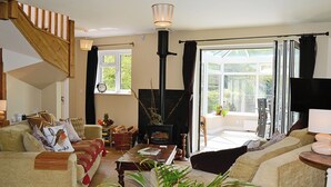 A cozy living room with a fireplace, comfortable seating, and a view of the outdoors. - 4 bedroom accommodation in Dunster, near Minehead (Dunster, near Minehead)