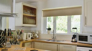 A kitchen with a wooden countertop, stainless steel appliances, and a window with a view of greenery. - 4 bedroom accommodation in Dunster, near Minehead (Dunster, near Minehead)