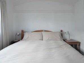 Un lit avec une tête de lit en bois, deux tables de chevet et deux lampes.
