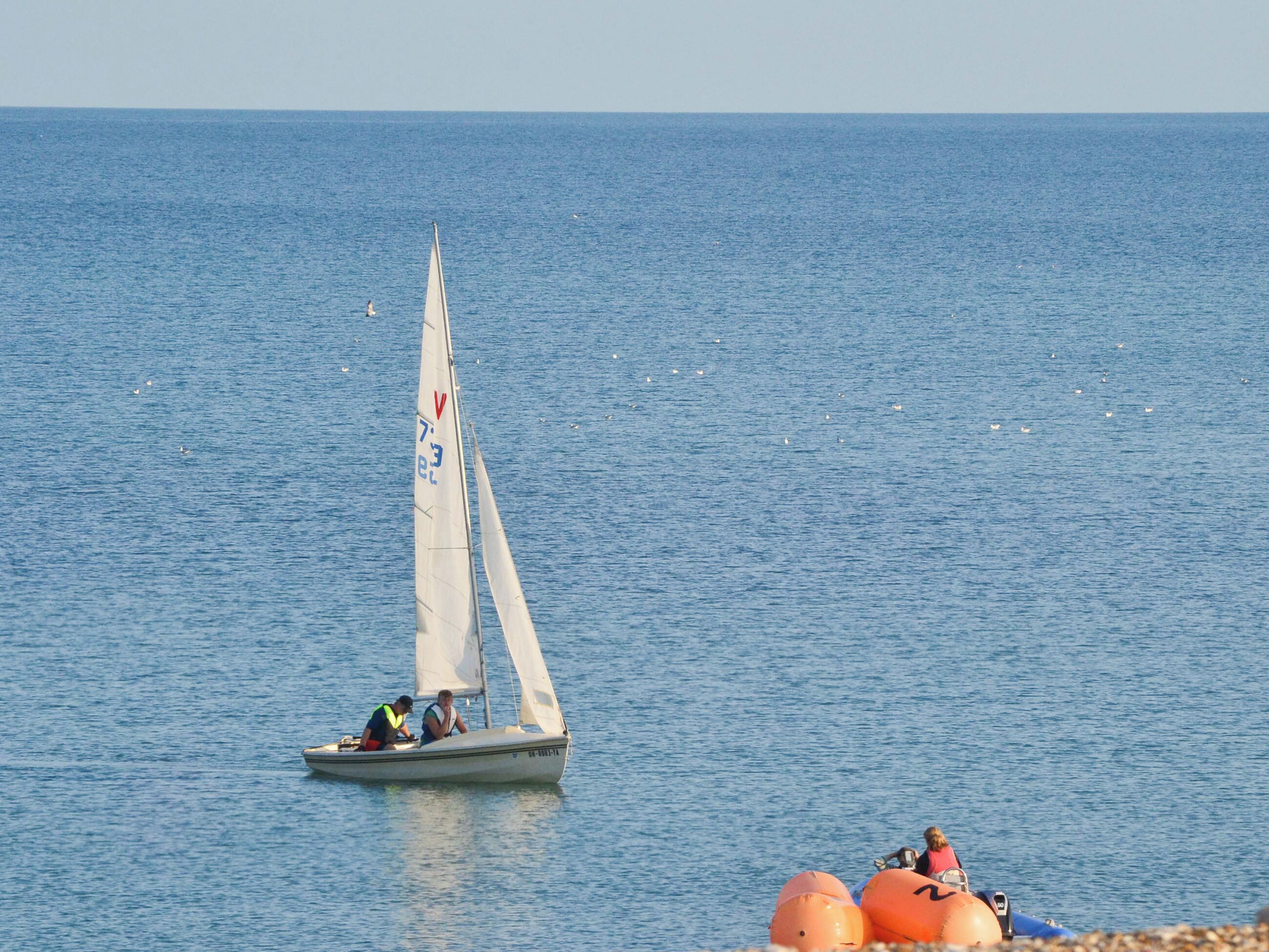A sailboat with two people on the water.