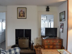 A living room with a fireplace, a television on a wooden cabinet, a wicker chair, and a dining table.