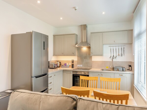 A compact kitchen with a refrigerator, stove, and dining area with chairs and a table.