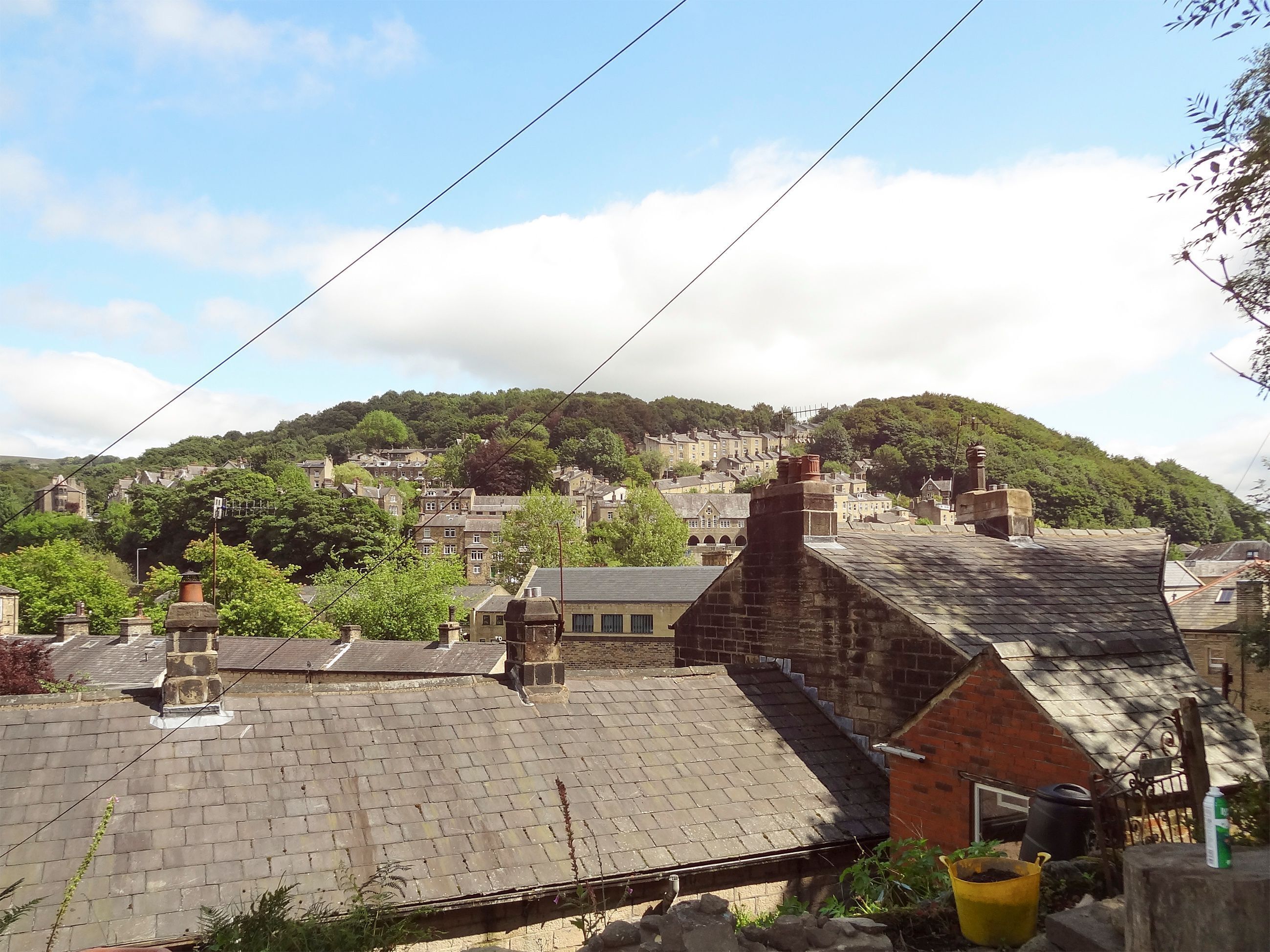A residential area with houses, a hill in the background, and a clear sky.