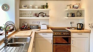 A compact kitchen with a sink, stove, oven, and a countertop with various kitchen items.