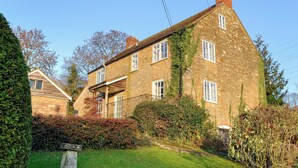 A stone house with a sloped roof, multiple windows, and a small porch.