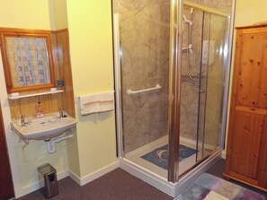 A bathroom with a glass-enclosed shower, a sink with a mirror, and a wooden cabinet. - 1 bedroom accommodation in Castletown, near Thurso (Castletown, near Thurso)