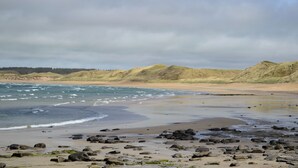 A beach with rocky terrain and dunes in the background. - 1 bedroom accommodation in Castletown, near Thurso (Castletown, near Thurso)