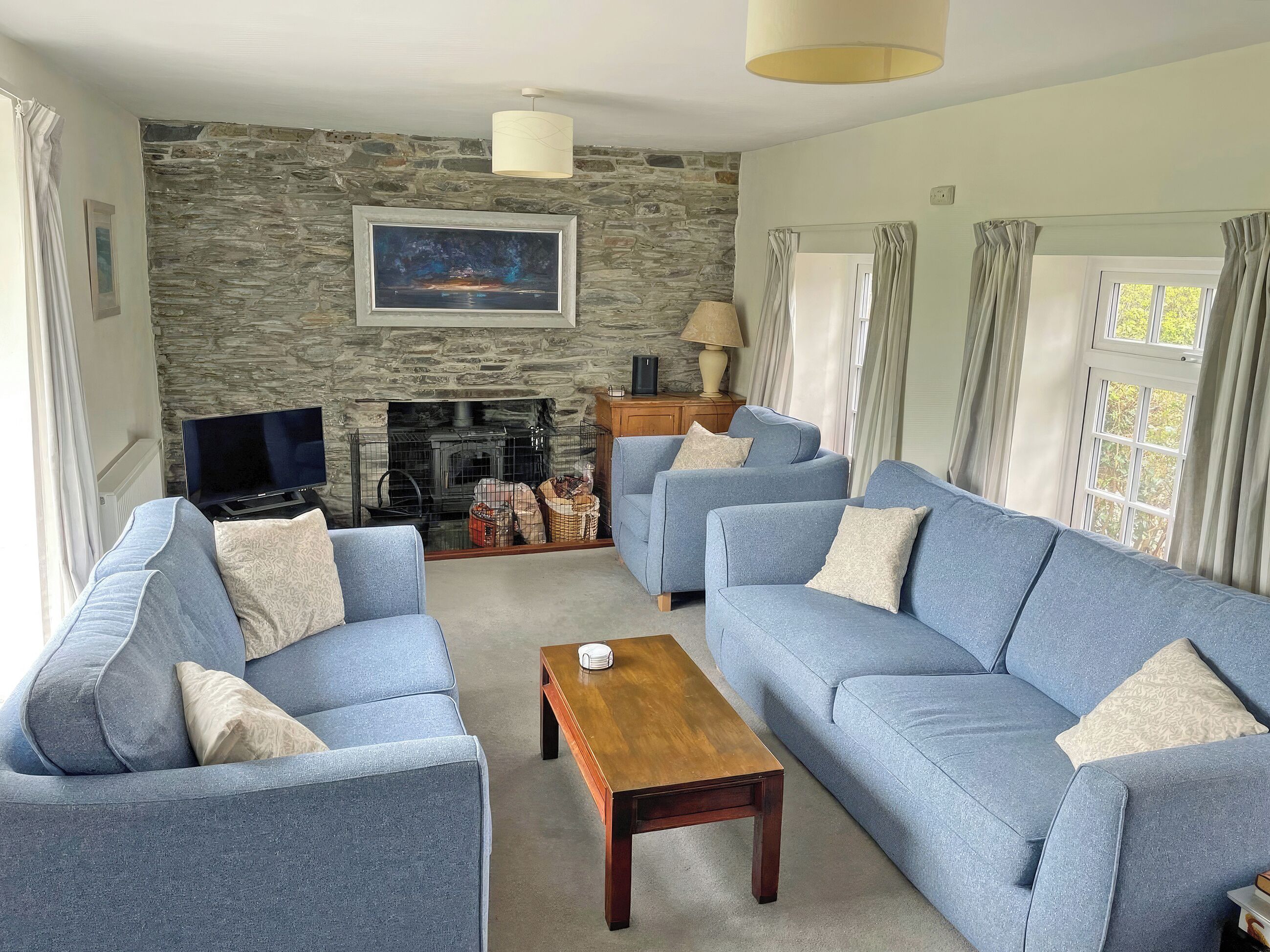 A living room with a stone wall, a fireplace, a television, and two sofas.