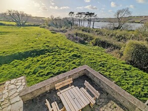 A stone bench with a table in a grassy area with a view of a river and hills. - 4 bedroom accommodation in Edmonton, near Wadebridge (Edmonton, near Wadebridge)