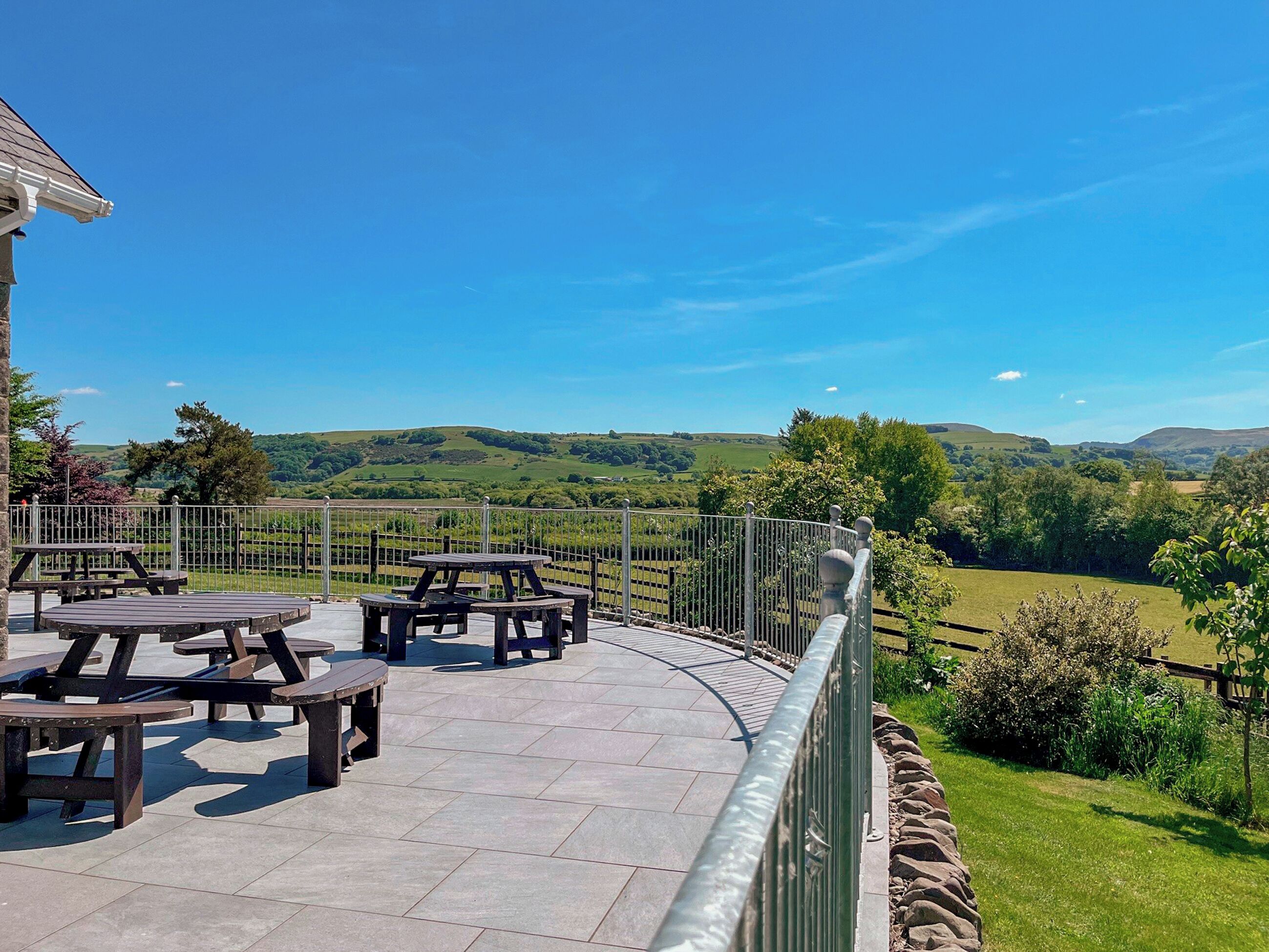 Eine Terrasse mit Picknicktischen mit Blick auf eine reizvolle Landschaft.