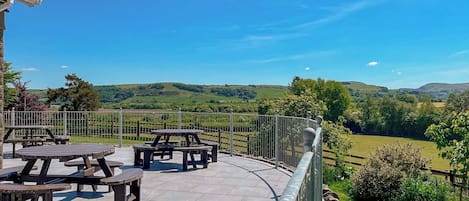 A patio with picnic tables overlooking a scenic landscape.