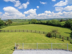 A fenced outdoor area with a view of rolling hills and a clear sky.