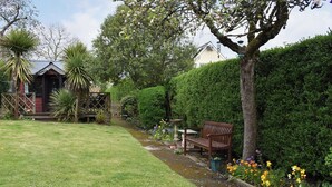 A garden with a bench, a small wooden structure, and a variety of plants. - 2 bedroom accommodation in Charmouth (Charmouth)