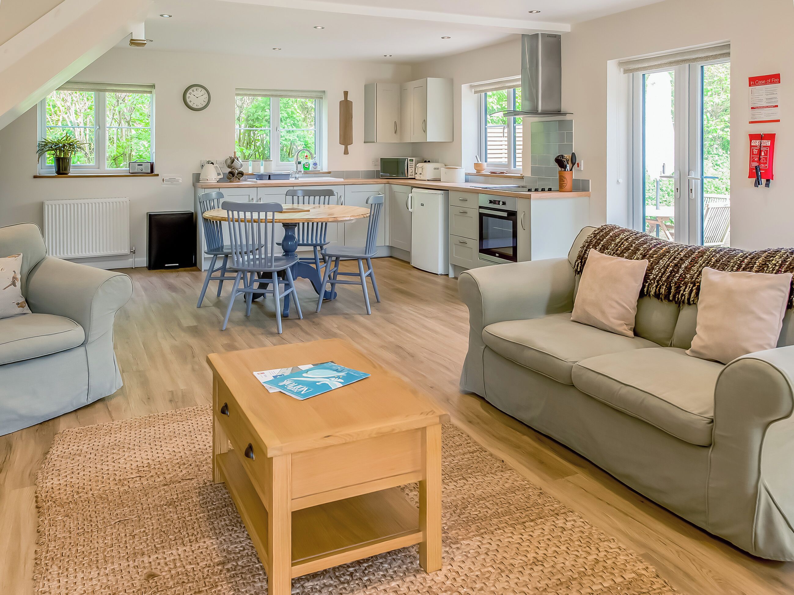 A modern living room with a sofa, a coffee table, and a dining area with chairs and a table.