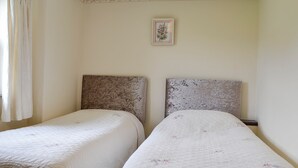 Two single beds with floral-patterned bedding, a plain wall, and a framed floral artwork above the beds. - 2 bedroom accommodation in Caldbeck, near Keswick (Caldbeck, near Keswick)