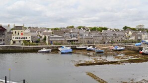 A harbor with boats docked, a building labeled "Nigel Warren Ltd.", and a stone wall. - 3 bedroom accommodation in Castletown (Castletown)