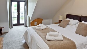 A bedroom with a bed, a chair, a nightstand, and a window with curtains. - 3 bedroom accommodation in Castletown (Castletown)