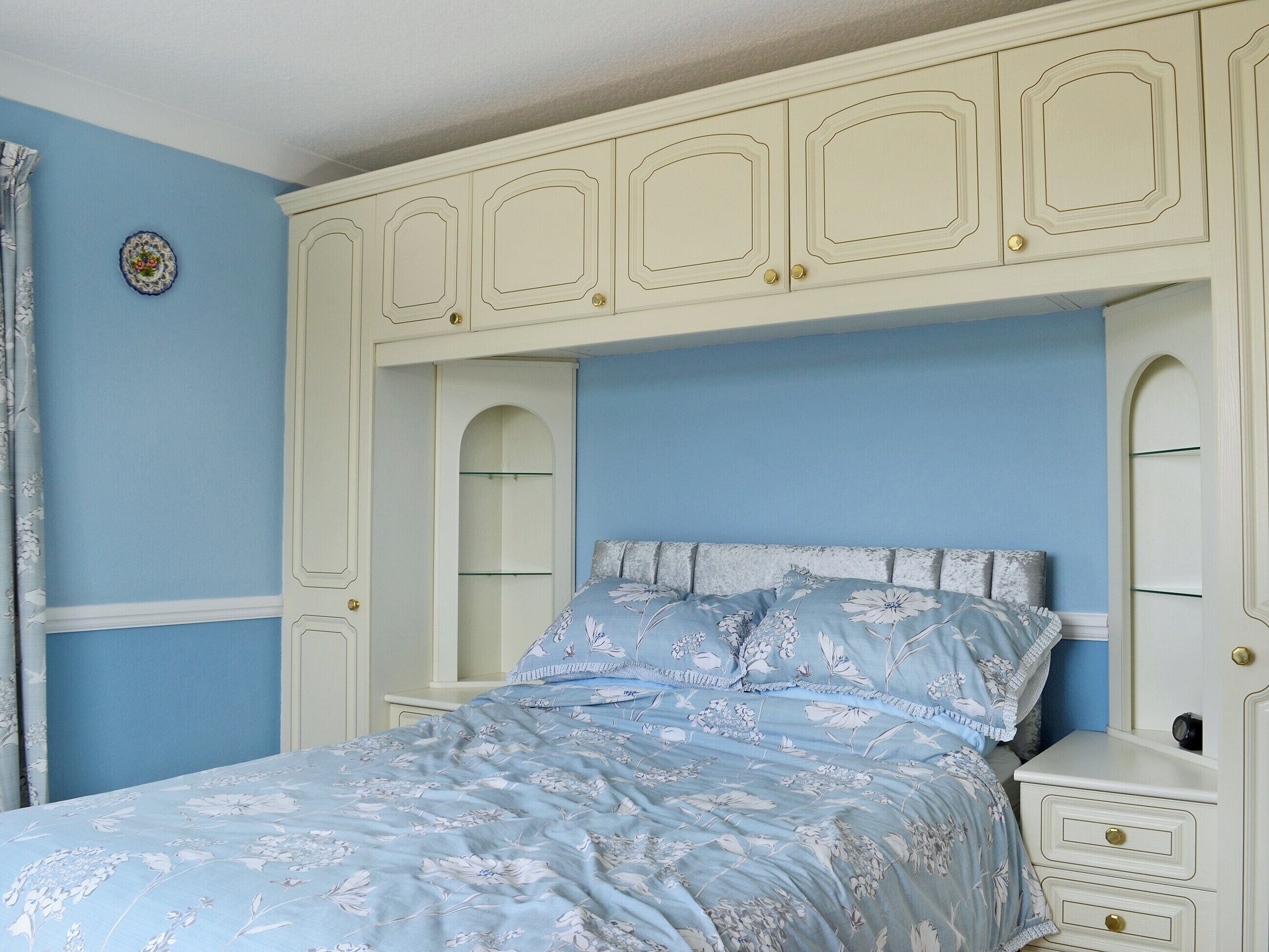 A bedroom with a bed, a nightstand, and a wardrobe.