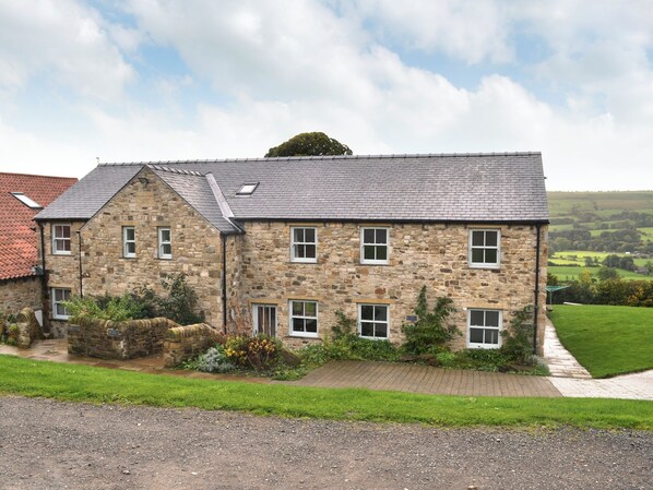 A stone building with multiple windows and a sloped roof.