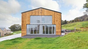 A modern wooden building with large windows and a sloped roof, situated on a grassy hill with a clear sky. - 6 bedroom accommodation in Wolsingham, near Stanhope (Wolsingham, near Stanhope)