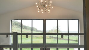 A room with a large window overlooking a grassy landscape, a ceiling light fixture, and a door with a handle. - 6 bedroom accommodation in Wolsingham, near Stanhope (Wolsingham, near Stanhope)