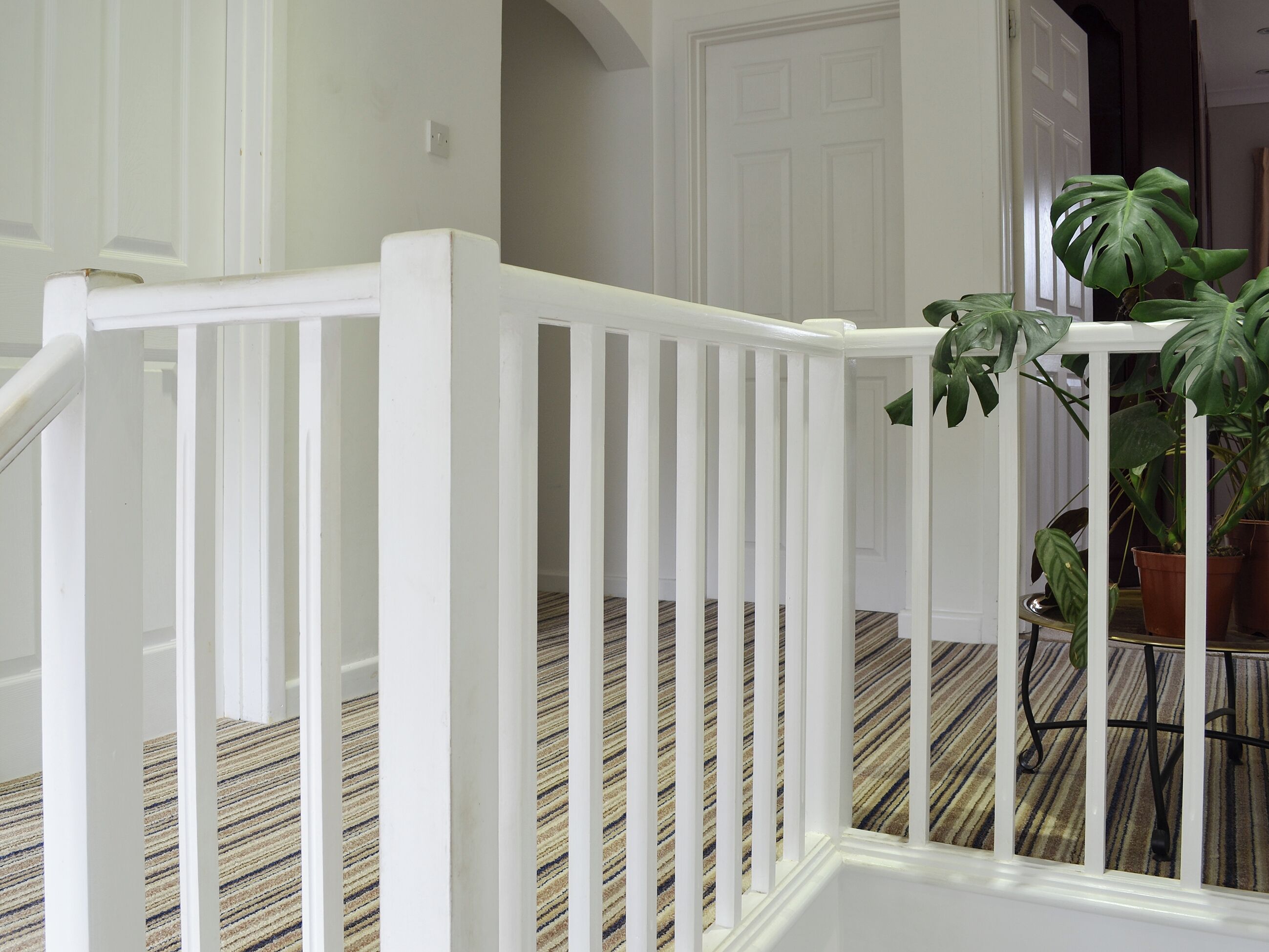 A staircase with white railings and a striped carpet.