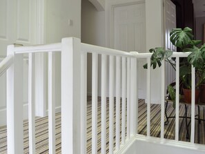 A staircase with white railings and a striped carpet.