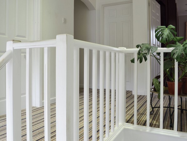A staircase with white railings and a striped carpet.