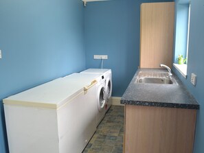A laundry area with a washing machine and dryer, a sink, and a window with a view.