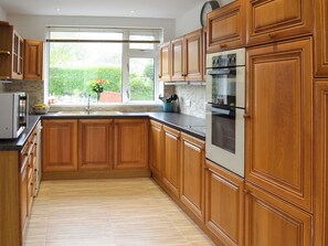 A kitchen with wooden cabinets, a built-in oven, and a window with a view of greenery.