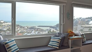 A room with a large window overlooking a coastal town and the sea. - 3 bedroom accommodation in Mevagissey (Mevagissey)