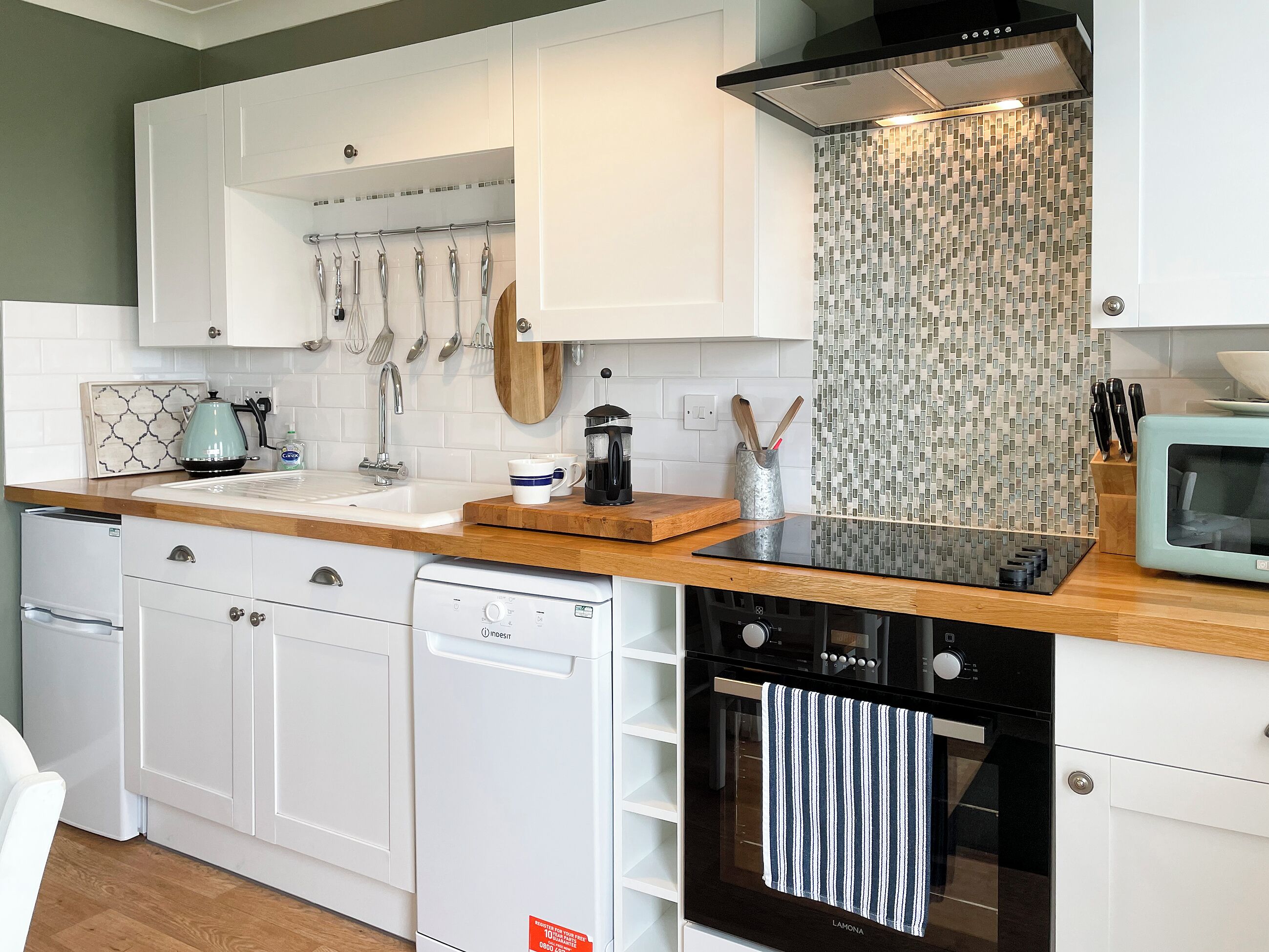 A modern kitchen with white cabinetry, a black stove, and a microwave.