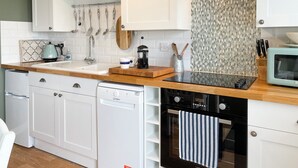 Una cocina moderna con armarios blancos, una estufa negra y un microondas.