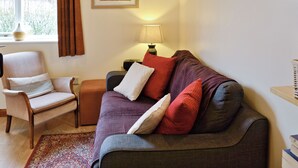 A cozy living room with a sofa, armchair, and a small table with a lamp. - Jasmine Cottage - W41461 (Sturminster Newton)