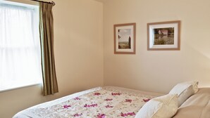 A bedroom with a bed, a window with curtains, and two framed pictures on the wall. - Jasmine Cottage - W41461 (Sturminster Newton)