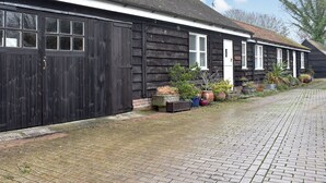 A row of black wooden houses with white windows and doors, a paved pathway, and potted plants in front. - Jasmine Cottage - W41461 (Sturminster Newton)