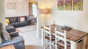 A dining area with a wooden table and chairs, a lamp, and a painting on the wall. - 4 Eldin Hall Cottages (Scarborough)