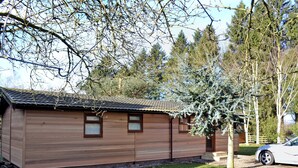 A small, single-story wooden cabin with a tiled roof, two windows, and a small porch. - 2 bedroom accommodation in Charlcot, near Masham (Charlcot, near Masham)