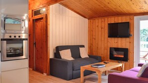 A cozy cabin interior with a kitchenette, a sofa, a table, and a fireplace. - 2 bedroom accommodation in Charlcot, near Masham (Charlcot, near Masham)