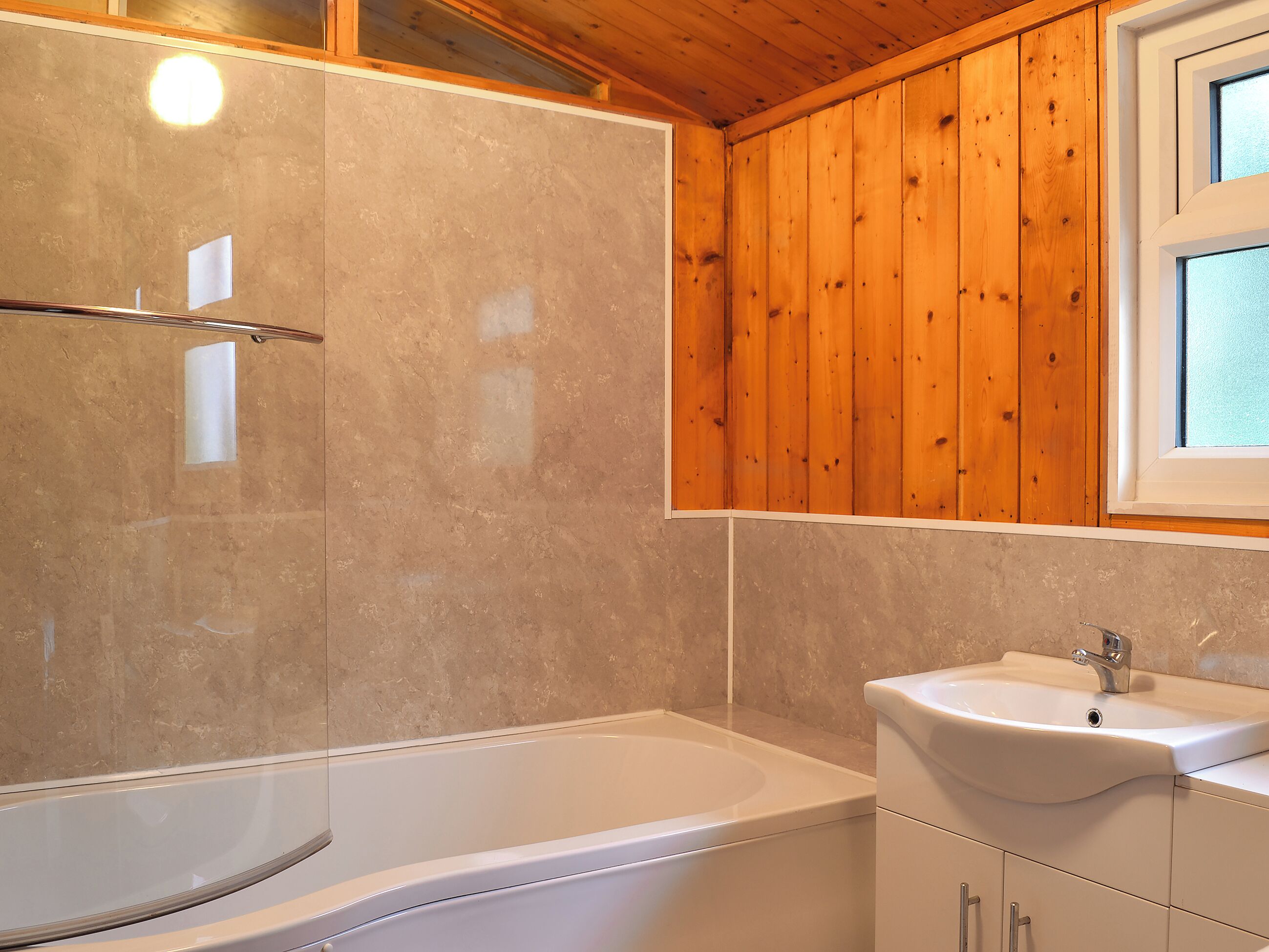 Un baño con bañera, lavamanos y paneles de madera en las paredes.