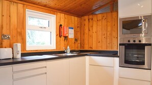 A kitchen with wooden walls, a window, a sink, a toaster, a kettle, and a built-in oven. - 2 bedroom accommodation in Charlcot, near Masham (Charlcot, near Masham)