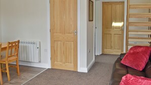 A room with a wooden door, a radiator, a brown leather sofa, and a wooden shelf. - 2 bedroom accommodation in Toynton-All-Saints, near Spilsby (Toynton-All-Saints, near Spilsby)