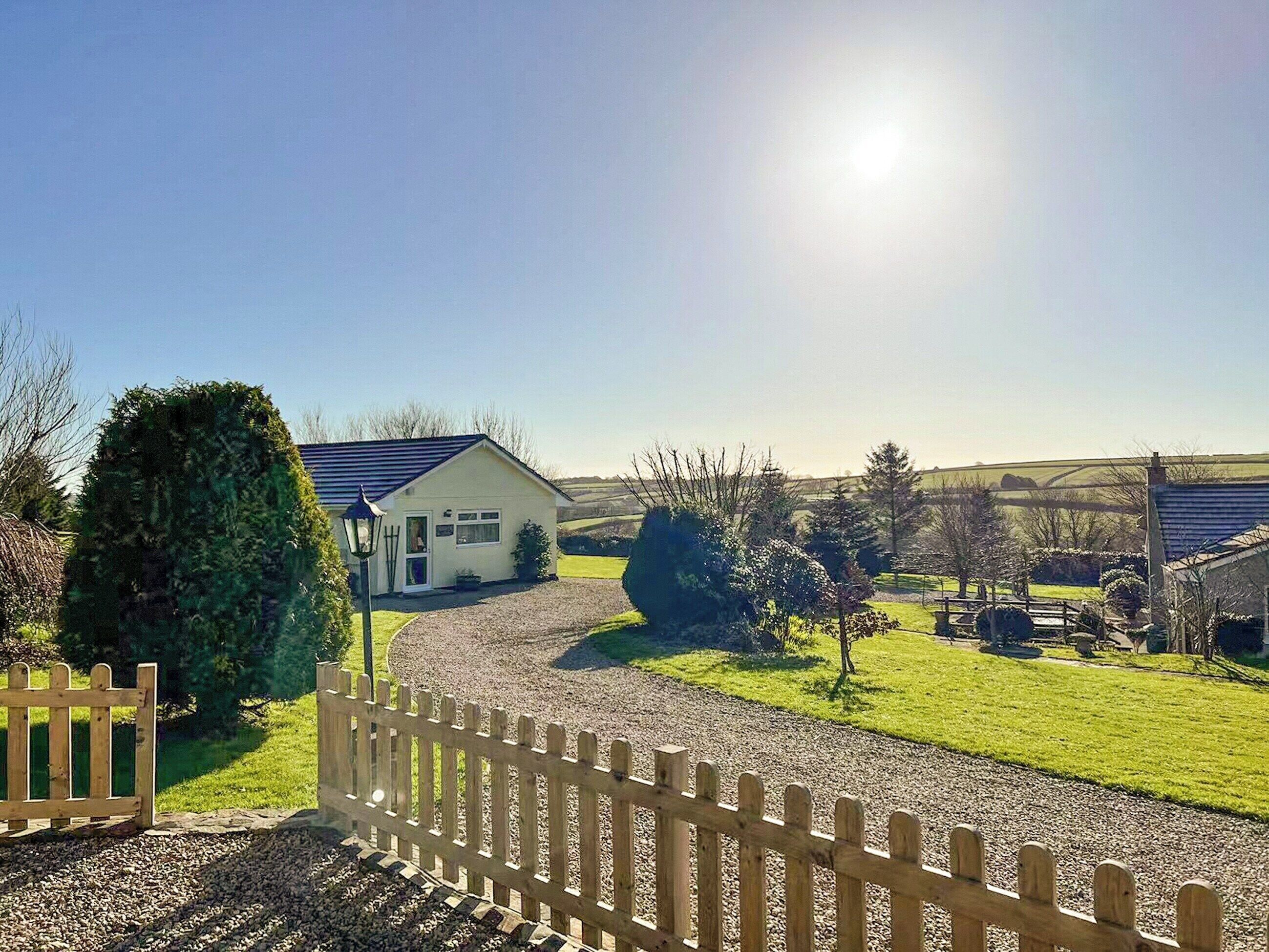 A house with a gravel driveway, a wooden fence, and a clear sky.