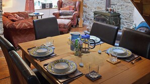 Un comedor con una mesa de madera dispuesta para cuatro personas, rodeada de sillas de cuero.